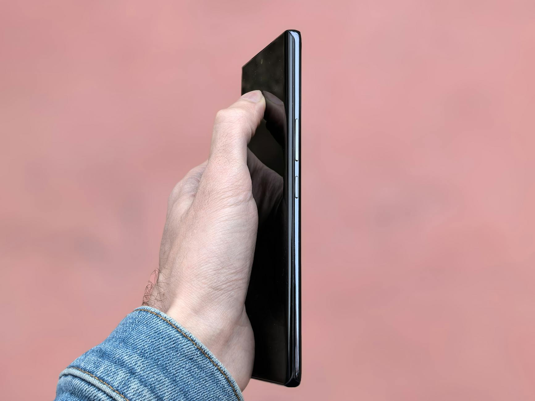 Close-up of Hand Holding Smartphone Against Pink Background