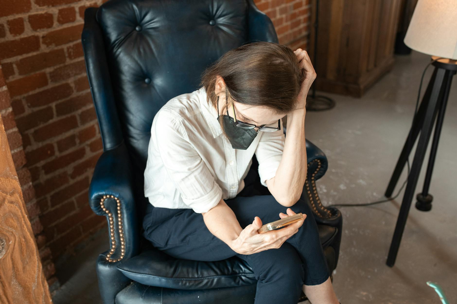 A Woman Sitting on an Armchair Using Her Smartphone