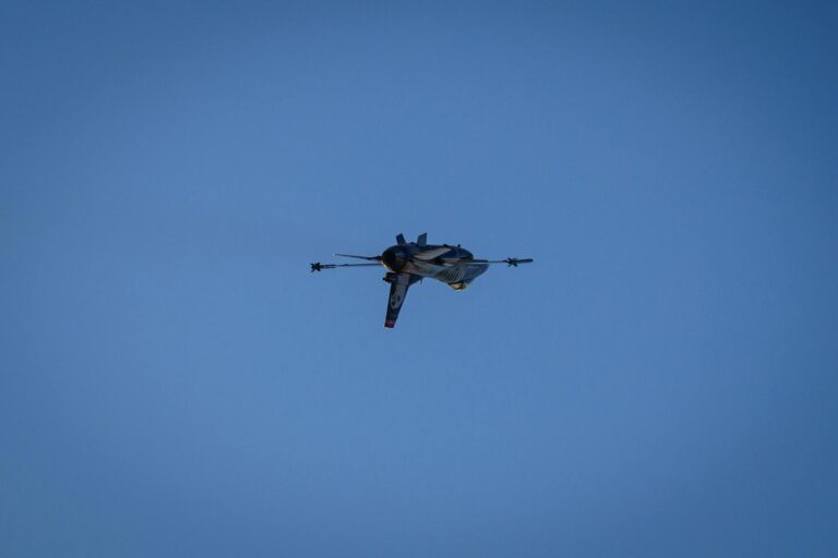 A fighter jet gracefully flying high against a clear blue sky.