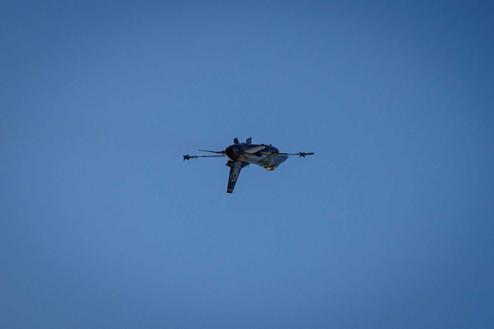 A fighter jet gracefully flying high against a clear blue sky.